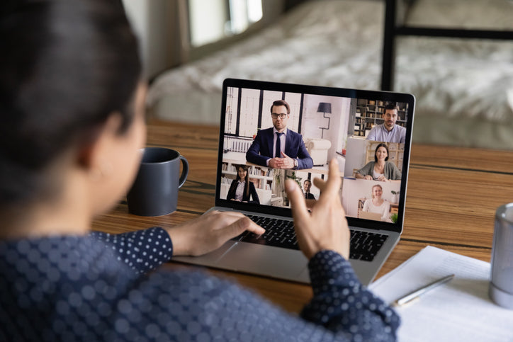 Person participating in a video call on a laptop with multiple participants displayed on the screen.